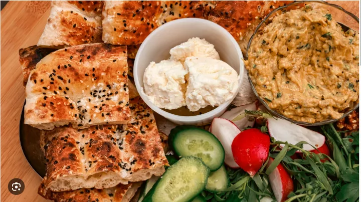 Fresh bread with cheese, vegetables, and a savory dip